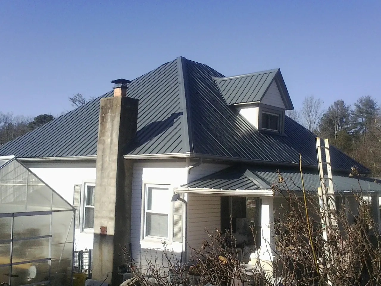 Dark blue standing seam metal roof on a white farmhouse with dormer — Slate & Tile Roof Repair by Roofing Brothers in Pittsburg