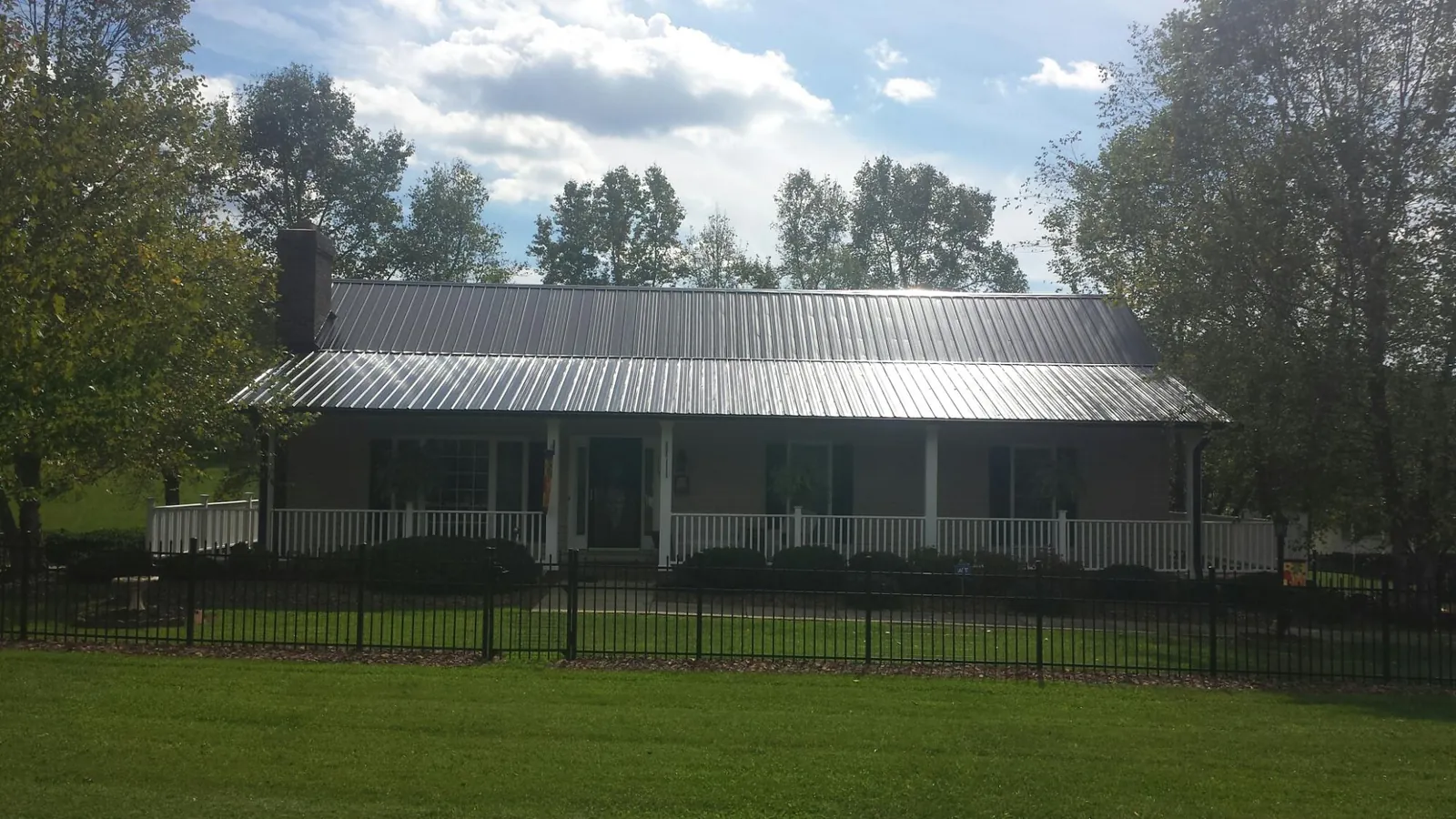 Gray metal roof on a brick ranch with a full width front porch — Gutter Guard Installation work by our crew in Pittsburg