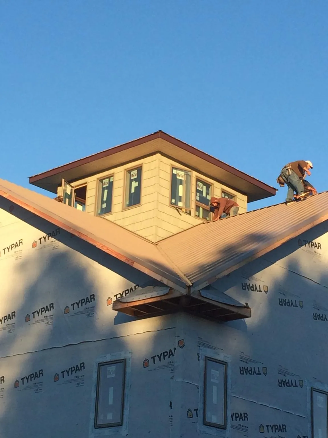 Roofers working around a rooftop cupola on a new metal roof at sunset — Roof Waterproofing in Pittsburg by Roofing Brothers